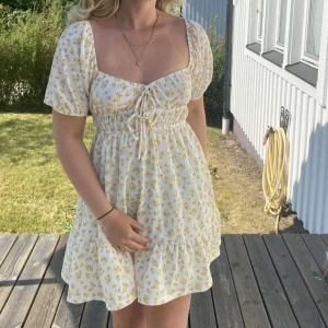 Gul blommig klänning - Klänning med blommigt mönster i gult och vitt. 