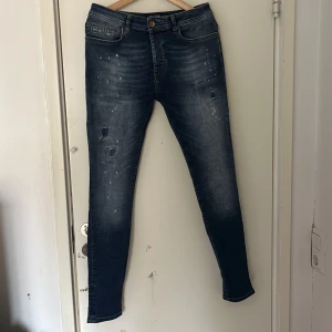 Blå jeans från Cars Jeans - Snygga blå jeans från Cars Jeans med slitna detaljer och en knappgylf. De har en klassisk femficksdesign och en bekväm passform. Perfekta för en avslappnad stil. Storleken är 32/32 och har en slim fit modell.