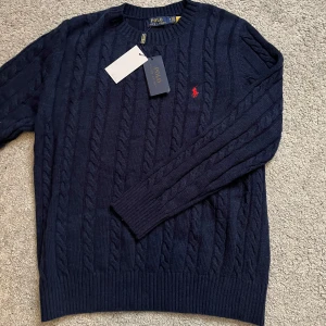 Mörkblå stickad tröja från Polo Ralph Lauren - Säljer en snygg mörkblå stickad tröja från Polo Ralph Lauren med kabelstickat mönster. Perfekt nu inför våren! Kom dm vid frågor.