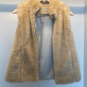Lurvig väst - Beige lurvig skön väst som är helt oanvänd. I super fint skick. Skriv vid eventuella frågor! Den är ursprungligen i storlek 152 men är större i storlek och passar XS.