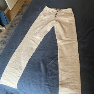 Beige byxor från Object - Snygga beige byxor från Object med fem knappar framtill. Byxorna har en klassisk design med två bakfickor och hällor för bälte. Perfekta för en stilren look.