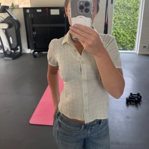Vit och grön rutig blus - Säljer en söt vit och grön rutig blus med korta ärmar och knappar fram till. Lite mer färg i vardags outfiten otroligt snygg