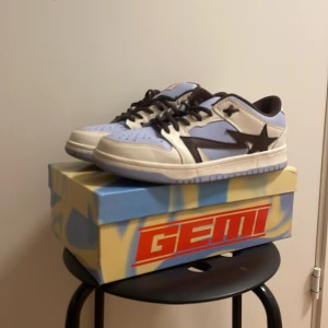 Dunk från Gemi - Snygga sneakers från Gemi i blått och vitt med en svart stjärndetalj på sidan. Skorna har snörning och en text på hälen som säger 'where stars go to die'. Perfekta för en cool och avslappnad stil.