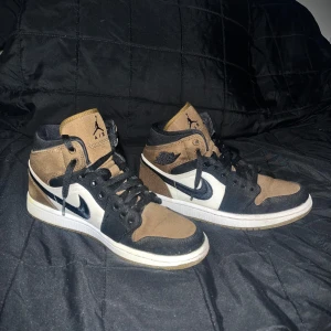 Air Jordan 1 höga sneakers - Snygga Air Jordan 1 höga sneakers i en cool färgkombination av brunt, svart och vitt. Skorna är i skick 8/10, säljer skorna pågrund av att jag har växt ut dem o köpte dem för ungefär 2 år sedan.