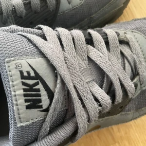 Grå Nike Air Max sneakers - Snygga grå Nike Air Max sneakers med klassisk design och bekväm passform. Skorna har en synlig Air-enhet i sulan för extra dämpning och komfort. De är tillverkade i syntetmaterial med snörning och har en subtil Nike-logga på sidan. Kan duskutera priset.