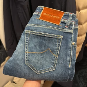 Jacob Cohen jeans  - Snygga blå jeans från Jacob Cohen med klassisk femficksdesign och kontrasterande sömmar. Jeansen har en knappgylf och Perfekta för en stilren look.