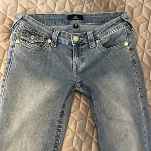 Blå jeans från True Religion - Ljusblåa jeans i storlek 26 som är bootcut och lågmidjade. Jag säljer jeansen för de har blivit för stora för mig. De är uppsydda och är perfekta i längden för mig som är 163 cm. Midjemått 37cm, inre benlängd 74 cm. 💕