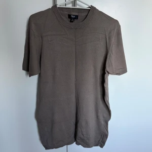 Beige kortärmad tröja från Smog - Säljer en stilren beige kortärmad tröja från Smog. Tröjan har en rund halsringning och är tillverkad i ett mjukt material som ger en bekväm passform. Perfekt för en avslappnad look.