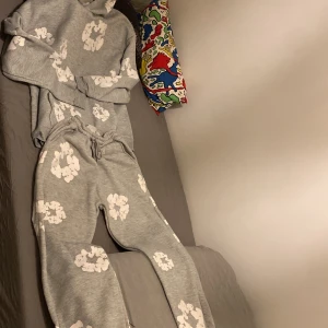 Grå set från denim tears - Säljer en grå hoodie och byxor från Denim Tears med ett unikt vitt blommönster. Säljer för den är för stor. M men passar S