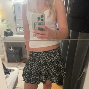 Volang kjol - Svart blommig volang kjol från lager 157. Storlek 160 men passar S/34 och även Xs/32. Säljer då den inte kommit till användning. Använd fåtal gånger 