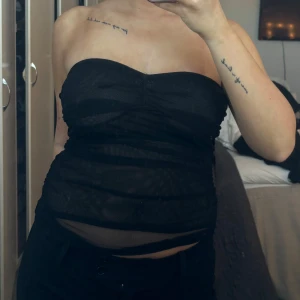 Svart tubtopp - Säljer en stilren svart tubtopp med en elegant och enkel design. Toppen är perfekt för en kväll ute och har en smickrande passform. Den är ärmlös och kan enkelt matchas med olika outfits.