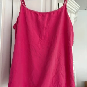 Rosa linnetopp från Joy of Love - Säljer en snygg rosa linnetopp från Joy of Love. Perfekt för varma dagar med sin enkla och stilrena design. Toppen har smala axelband och är tillverkad i ett mjukt material.