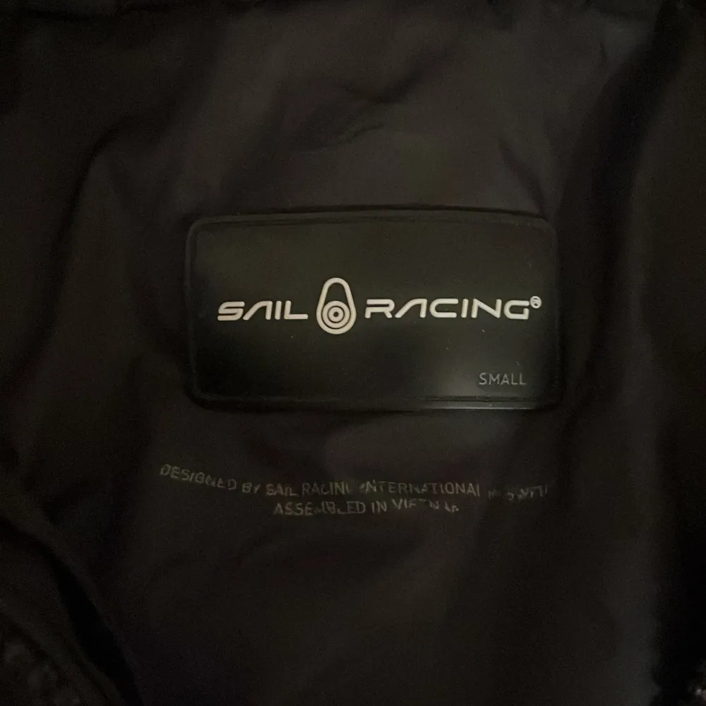 Säljer en svart dunjacka från Sail Racing. Jackan har en stilren design med dragkedja och huva. Perfekt för dig som gillar värme.. Takit.