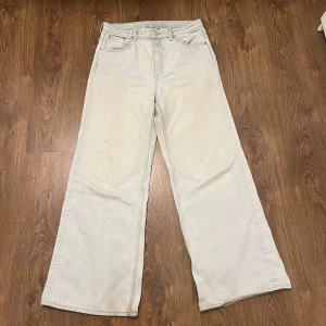 Ljusa jeansbyxor från Weekday - Säljer ett par ljusa jeansbyxor från Weekday i modellen ACE med en avslappnad och bred passform. Byxorna har en klassisk femficksdesign och är tillverkade i ett slitstarkt denimtyg. Det finns en fläck på ena bakfickan som inte går bort men det är inget som jag upplevt som störande!