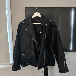 Svart skinnjacka  - Snygg svart skinnjacka från Missguided med dragkedja och bälte. Jättefint skick och perfekt nu till våren 🌸köpt på Nelly 