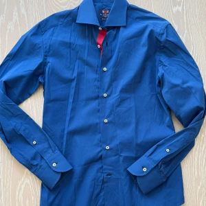 Blå skjorta från La Chemise - Snygg blå skjorta från La Chemise i slim fit. Skjortan har långa ärmar och knappar framtill. Perfekt för en stilren look.