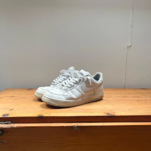 Vita Nike Air Force sneakers - Säljer ett par klassiska vita Nike Air Force sneakers. Observera att sulan är ganska sliten. Skorna är i behov utav en tvätt. 