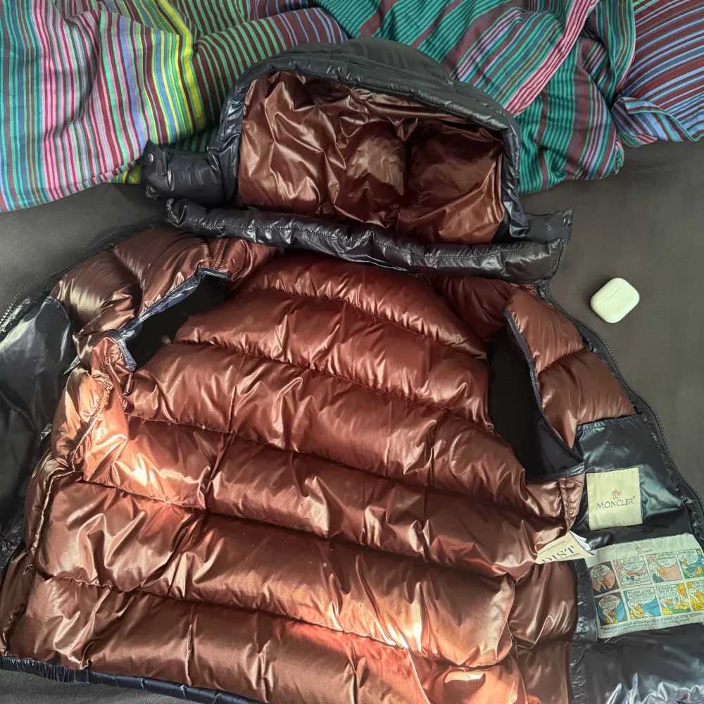 Snygg mörkblå dunväst från Moncler med glansig yta och dragkedja framtill. Västen har en hög krage och praktiska fickor med dragkedjor. Perfekt för sommaren när du vill hålla stilen. Kvitto finns, pris ej hugget i sten. . Takit.