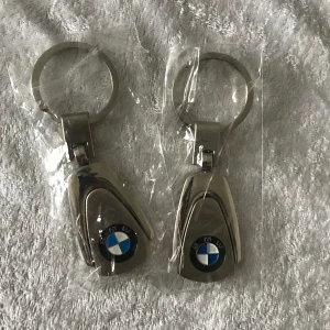 Bil Nyckelring  - Säljer två stilrena nyckelringar i metall med BMW och Mercedes logotyper. Perfekta för bilentusiaster som vill ha en elegant touch på sina nycklar. Nyckelringarna är förpackade i plast.  135kr/2st /bild, helt ny 