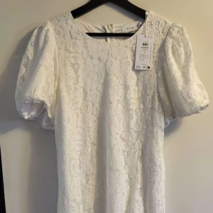 Vit spetsklänning från Vila - Säljer en vit spetsklänning från Vila med korta puffärmar som jag hade tänkt att ha till studenten men hittade en annan jag tyckte om mer. Så den är endast testad men lappen kvar!  Den stängs med en dragkedja i ryggen.❣️