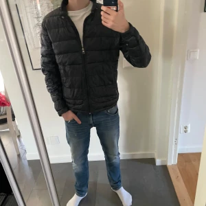 Svart pufferjacka från Moncler - Säljer en stilren svart pufferjacka från Moncler. Jackan har en dragkedja framtill och är långärmad. Perfekt för kyligare dagar med sin quiltade design som håller värmen. Moncler-loggan syns på ärmen. Två små hål. PRISET EJ HUGGET I STEN. Har kvitto. Köpt från Kaspers Heat!