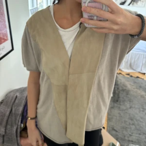 Beige mockaväst i kashmir  - Säljer en stilren beige mockaväst med korta ärmar. Så fin i cashmere och i bra fint skick från italienskt dyrt märke
