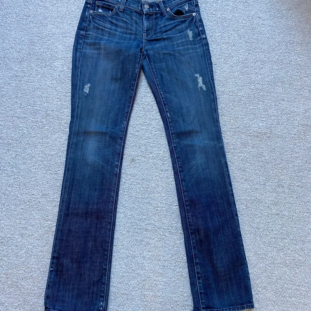 Snygga blå jeans från 7 For All Mankind med straight leg och slitna detaljer. Jeansen har en klassisk femficksdesign och en knappgylf. Perfekta för en avslappnad stil. Slita längst ner på baksidan (se bild 4). 💕Midjemått (rakt över) 34 cm & innerbensmått 79 cm.. Farkut & Housut.