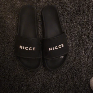 Svarta sandaler från Nicce - Snygga svarta sandaler från Nicce med märkets logga i vitt på ovandelen. 