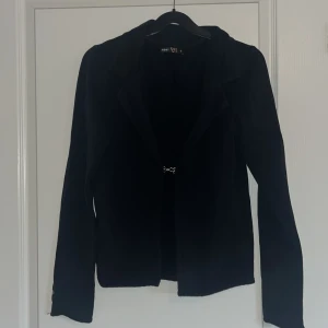 Svart kavaj från Meandi - Stilren svart kavaj från Meandi i mjuk bomullsblandning med lång ärm och enkel knäppning framtill. Perfekt för en snygg och klassisk look. Materialet är 96% bomull och 4% elastan för extra komfort.