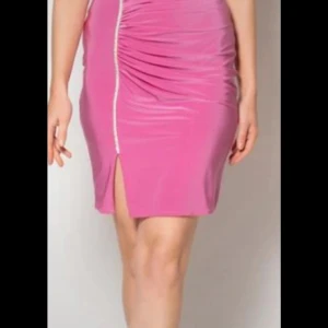 Rosa tight kortklänning med slits - Säljer en rosa tight kortklänning med snygg drapering och en dekorativ slits framtill. Klänningen har en markerad söm och är figurnära i modellen, perfekt för dig som gillar en feminin och trendig look.