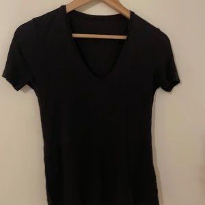 Svart v-ringad t-shirt - En stilren svart t-shirt med v-ringning och korta ärmar. Perfekt basplagg som passar till det mesta. T-shirten har en klassisk passform och är tillverkad i mjukt material för extra komfort. obs: tröjan är milt genomskinlig!!
