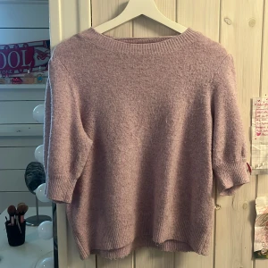 Ljuslila stickad tröja från Vero Moda - Supermjuk ljuslila stickad tröja från Vero Moda. Tröjan har rund halsringning, halvlånga ärmar och ribbade muddar vid ärmslut och nederkant. Perfekt för lager-på-lager och en chill look.