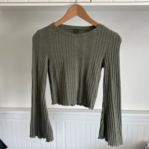 Grå ribbad croppad tröja från SHEIN - Säljer en grå ribbad croppad tröja från SHEIN. Tröjan har långa ärmar med lätt utsvängd form och är tillverkad i ett mjukt stickat material. Perfekt för lager-på-lager och enkel att matcha med olika outfits.