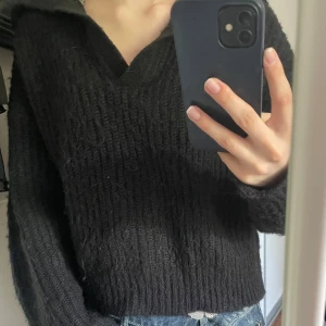 Svart stickad tröja med krage från Gina Tricot - Mysig svart stickad tröja från Gina Tricot i storlek S. Tröjan har en bred krage och v-ringning, samt långa ärmar. Perfekt för kyligare dagar och enkel att matcha till jeans eller kjol. Tröjan är använd några gånger