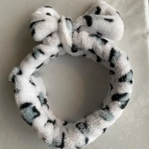 Vit fluffigt hårband med svart leopardmönster och rosett - mjukt diadem i vit färg med svart leopardmönster. Perfekt för att hålla håret borta vid sminkning eller hudvård. Använd en gång, väldigt stretchig och sitter jätte skönt, har väldigt mjukt material!❤️ pris kan självklart diskuteras!