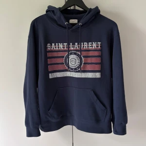 Saint Lourent hoodie - Säljer nu en väldigt eftertraktad hoodie från saint lourent, tröjan är äkta som ni ser på lappen | skick 9/10 | strlk M | ny pris 5000 kr | hör gärna av dig vid fler funderingar, kan tänka mig att gå ner i pris vid snabb affär. Modellen är 1,80 och väger 70 kg. 