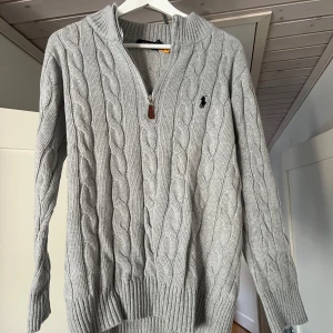 Ralph Lauren kabelstickad tröja grå - Säljer denna kabelstickade tröjan från Ralph Lauren då den satt lite för litet. Tröjan är sprillans ny, endast upppackad. Inga defekter, men skulle säga att den sitter mer som S än M. Vid minsta funderingar är det bara att höra av sig!