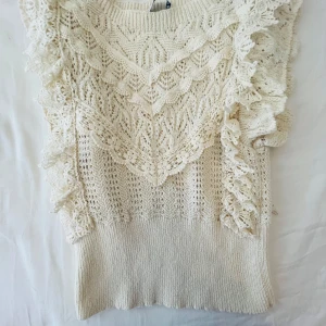 Vit spetsdetaljerad stickad tröja Zara - Supersöt vit stickad tröja med vackra spetsdetaljer och volanger längs axlarna. Tröjan har ett unikt mönster och bred ribbad nederkant. Perfekt för dig som gillar romantisk och feminin stil.