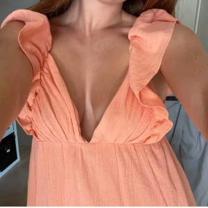 Orange H&M klänning - Lång orange klänning från H&M som inte säljs längre 🤍 fint skick. Storlek 38 men går att justera storleken bak i ryggen med snören. Kjolen är ca 100cm från under bysten