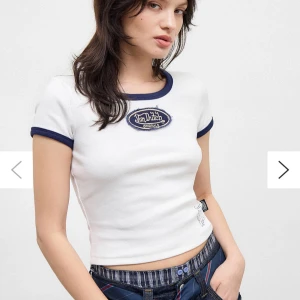 Vit t-shirt från Von Dutch med blå detaljer - Säljer en vit t-shirt från Von Dutch med blå ribbade kanter vid ärmslut och hals. Toppen har en broderad Von Dutch-logga framtill och ett tryckt VD-märke nedtill. Perfekt för en sportig och trendig look. Lappen är kvar och den är aldrig använd! (Original pris 510kr)