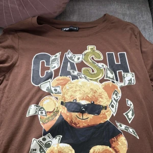 Brun t-shirt med björn och cash-tryck. - säljer då den inte passar längre. 