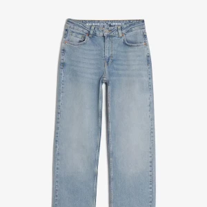 Ljusblå wide leg jeans från Gina Tricot - Säljer ett par ljusblå jeans från Gina Tricot med hög midja och raka, vida ben. Klassisk femficksmodell med gylf och knapp framtill samt läderpatch bak i midjan. Perfekta för en avslappnad och trendig look.