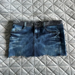 Jeanskjol med ugglepatch - Kort jeanskjol med detaljer och en ugglepatch på bakfickan. Längd: 27cm Midjemått: 42cm