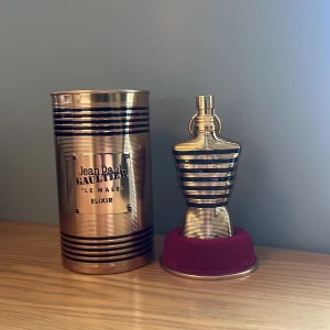 Jean Paul Gaultier Le Male Elixir Eau de Parfum - Det är ca halva kvar.                               Exklusiv herrparfym i en ikonisk guld- och svart randig flaska formad som en manlig torso. Kommer med original metallburk och röd bas. Doften är intensiv och modern, perfekt för dig som vill sticka ut.