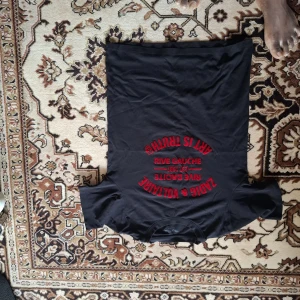 Svart t-shirt med röd text från Zadig & Voltaire - Svart t-shirt från Zadig & Voltaire med röd tryckt text på bröstet. Klassisk rund halsringning och korta ärmar. Perfekt för en cool och avslappnad stil.