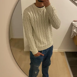 Vit stickad tröja från Only&sons - Säljer en vit stickad tröja med klassiskt kabelstickat mönster. Tröjan har rund halsringning och långa ärmar med ribbade muddar och nederkant. Perfekt för kyligare dagar och enkel att matcha med jeans eller chinos.