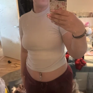 Vit ribbad polotopp från SHEIN - Säljer en vit ribbad polotopp från SHEIN i storlek M. Toppen har korta ärmar och en hög hals, vilket ger en stilren och enkel look. Perfekt att matcha med jeans eller kjol för en snygg outfit.