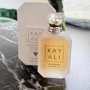 Kayali The Wedding Silk Santal 36 Eau de Parfum - Exklusiv parfym från Kayali i en frostad, åttakantig flaska med kristalliknande kork. Doften har noter av mousserande champagne, vit fresia, pink praliné, nektarin, sandelträ och sötad mysk. Flaskan rymmer 50 ml och kommer i elegant vit förpackning. Endast testad med 2 sprut 