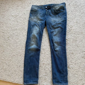 Blå jeansbyxor med raka ben - Klassiska blå jeansbyxor med raka ben och fem fickor. Byxorna har knappgylf och diskreta slitningar framtill för en avslappnad look. Passar perfekt till vardags och har en tidlös stil.