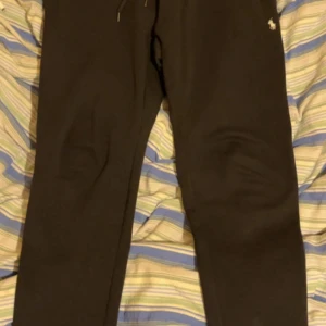 Svart hoodie och byxor från Polo Ralph Lauren - Säljer ett svart set från Polo Ralph Lauren med hoodie och matchande byxor. Hoodien har dragkedja, huva med snören och logga på bröstet. Byxorna har resår i midjan och logga på benet. Perfekt för en avslappnad stil. Helt ny oanvänd bara prislappen är borta  köpt för 1200kr men säljer för 700 vid snabb affär endast 600